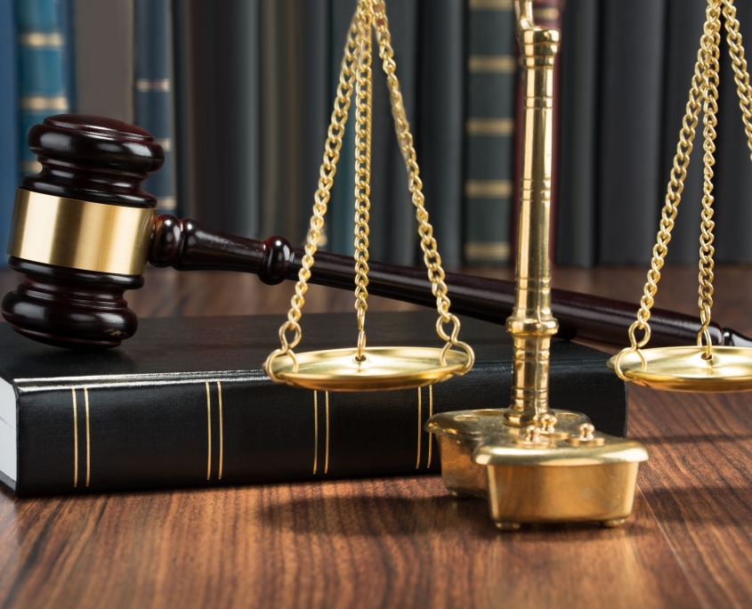 wooden gavel on book with golden scale on table