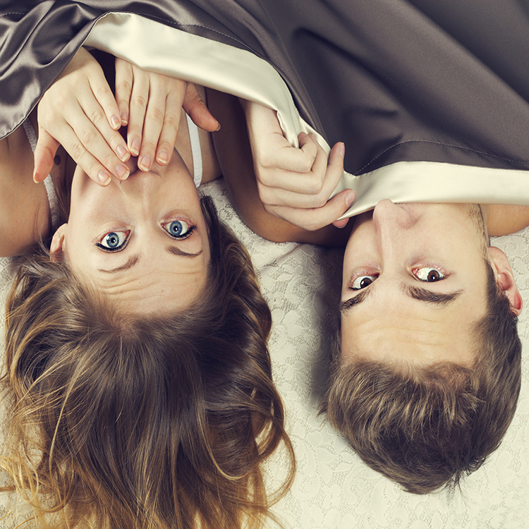 A couple underneath a blanket surprised by something